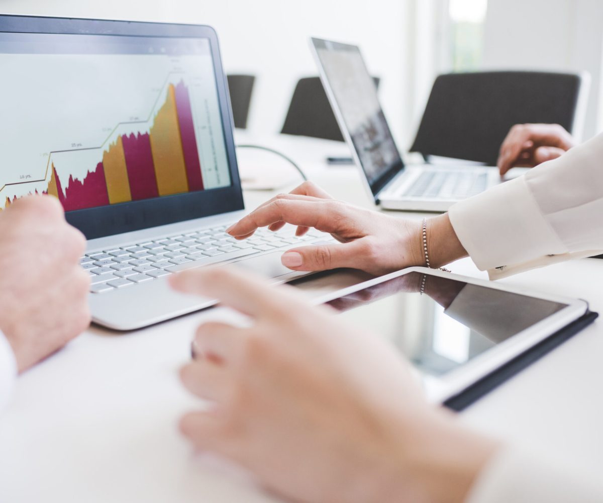 Cropped shot of businessmen and woman looking at laptop charts in office